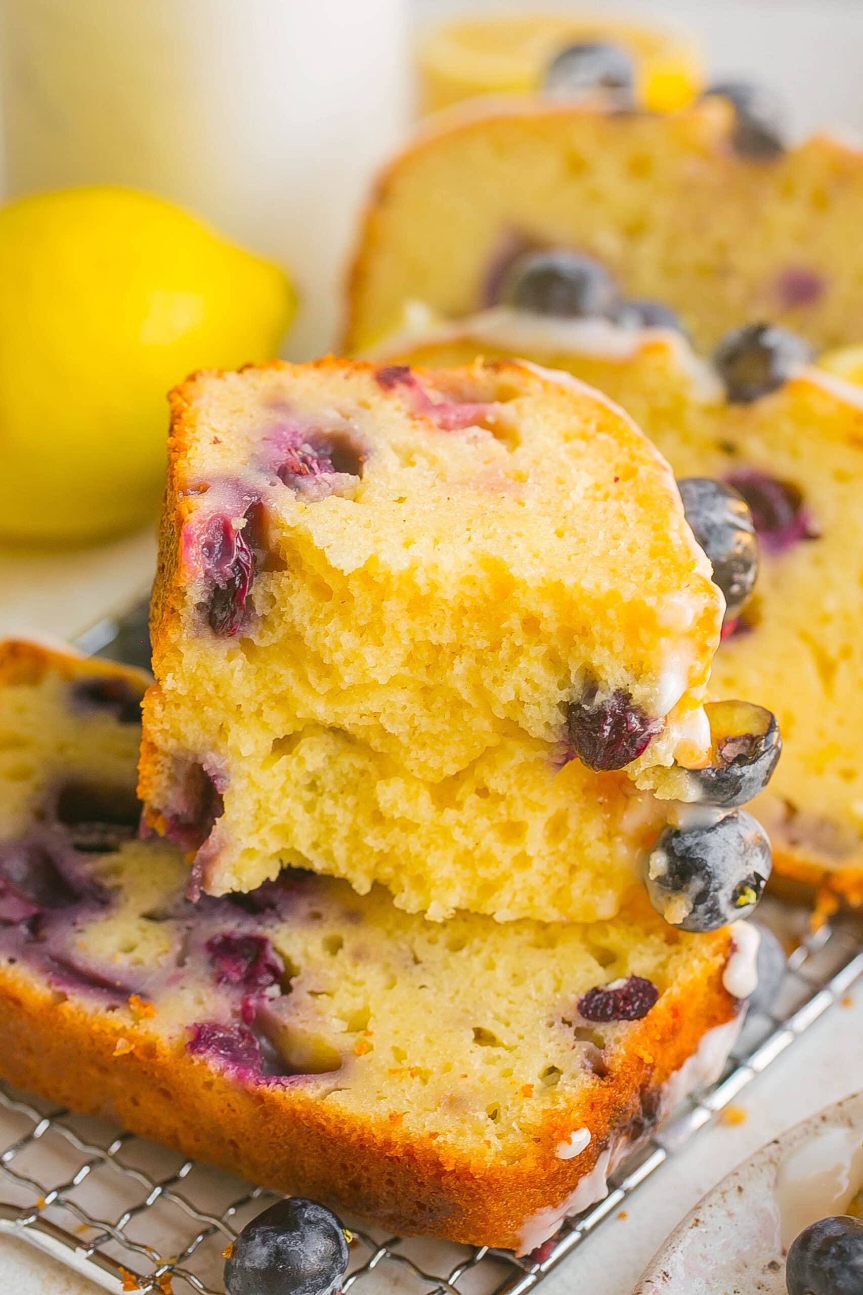 Stack of Lemon Loaf Cake with blueberries, cut in half and stacked on another slice.