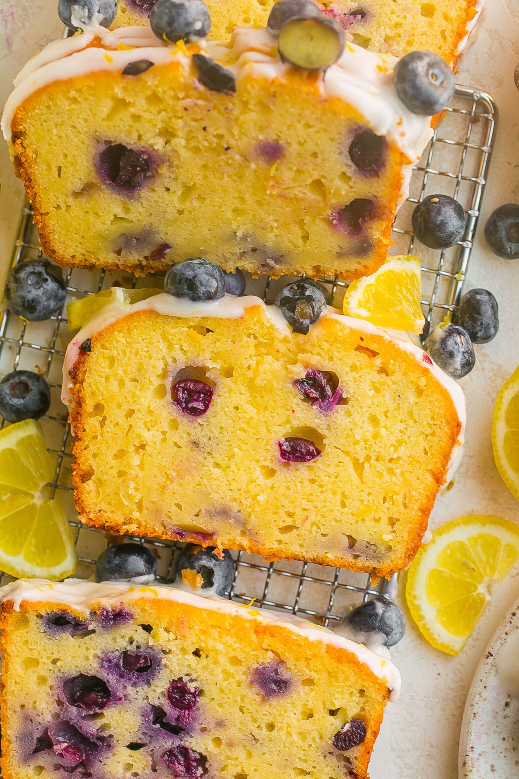 Slices of Blueberry Lemon Pound Cake with juicy blueberries, fresh lemon zest, and a simple lemon icing.