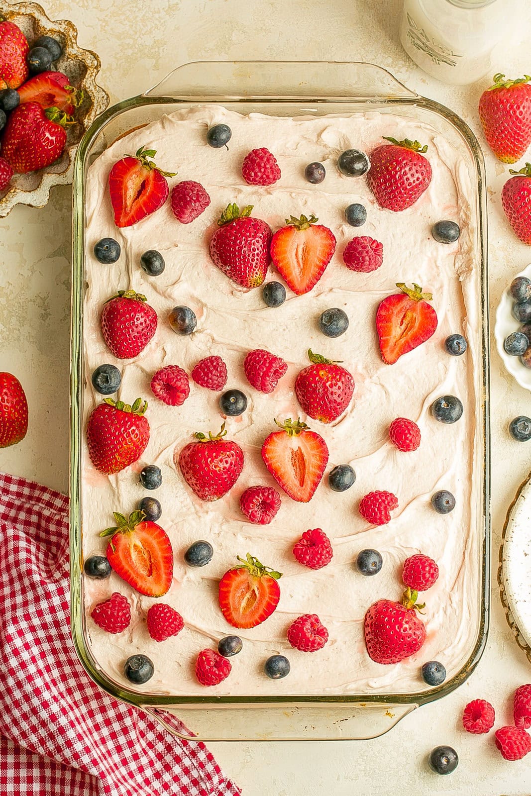 Fresh berry yogurt cake with a tender crumb, creamy frosting, and a topping of mixed summer berries.