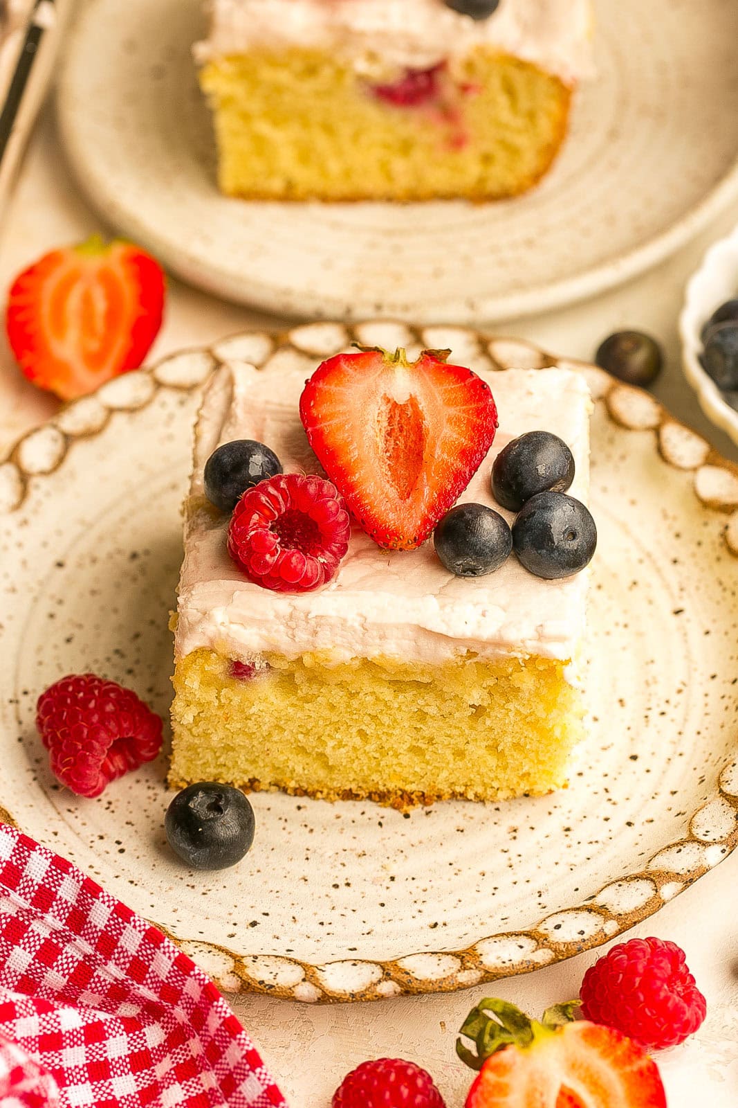 Slice of berry yogurt cake with fresh strawberries, blueberries, and raspberries baked into a moist sheet cake.