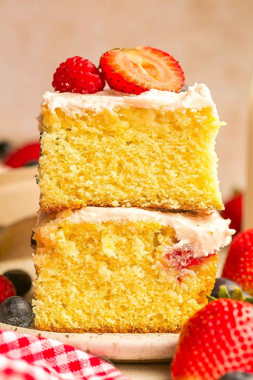 Berry Sheet Cake layered on top of each other with frosting and berries.