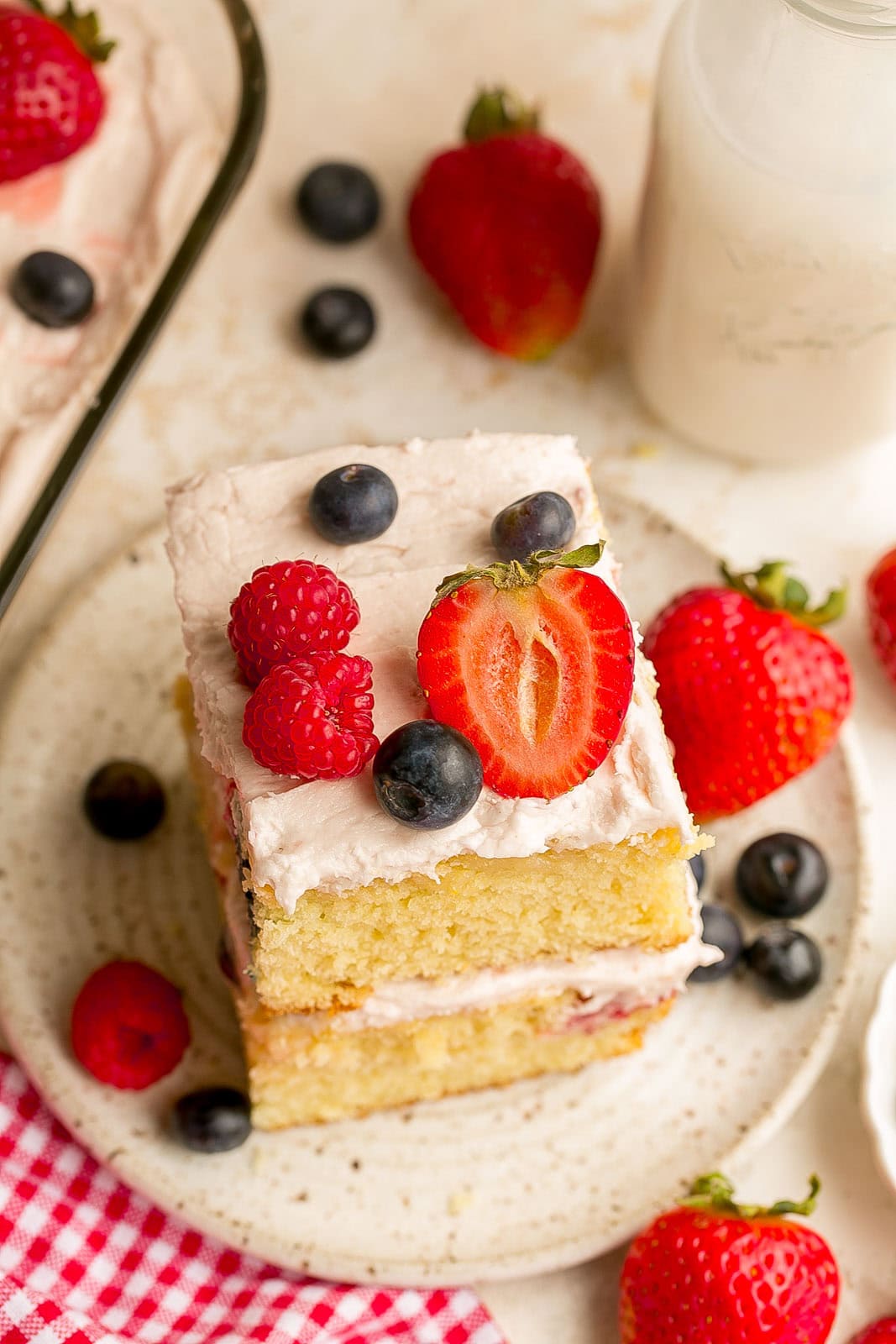A piece of soft and fluffy berry yogurt cake topped with buttercream frosting and an assortment of fresh berries.