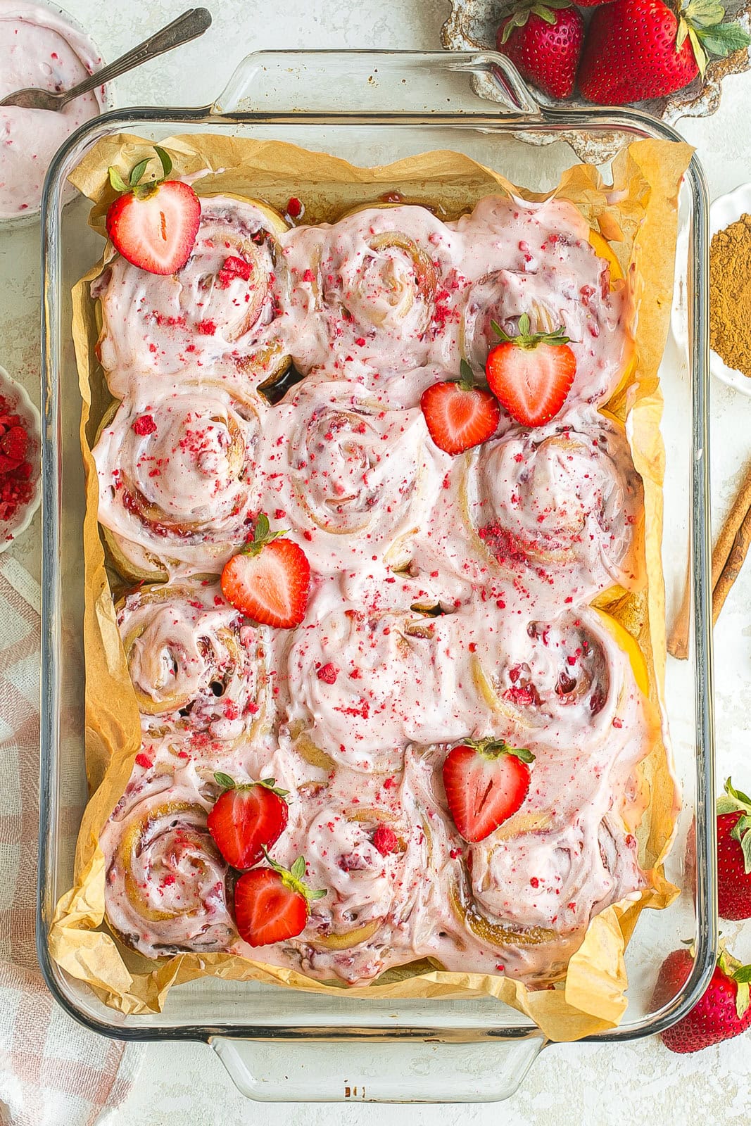 A batch of Soft Strawberry Cinnamon Rolls topped with strawberry cream cheese frosting.