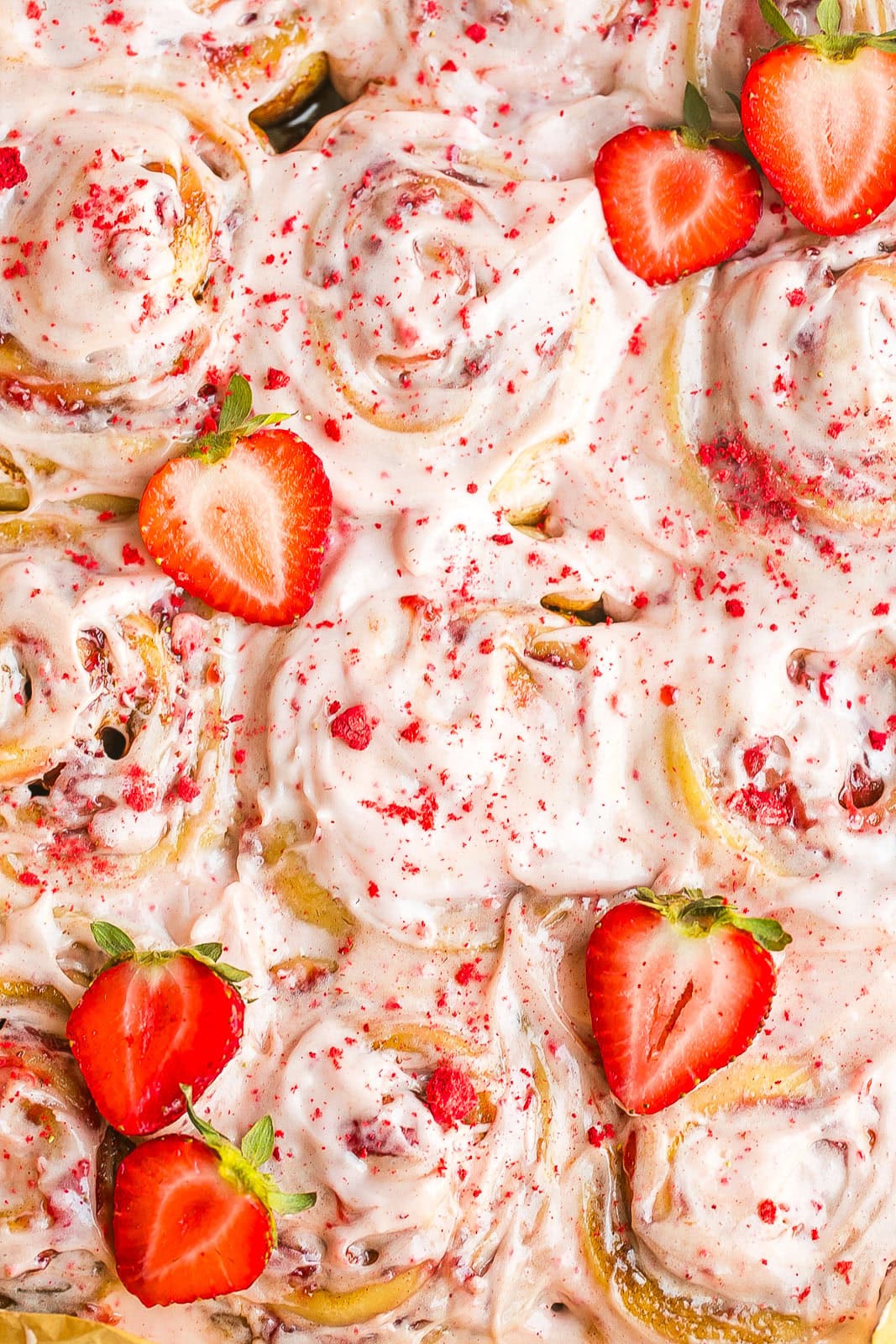 Sweet strawberry rolls topped with creamy frosting and sliced strawberries.