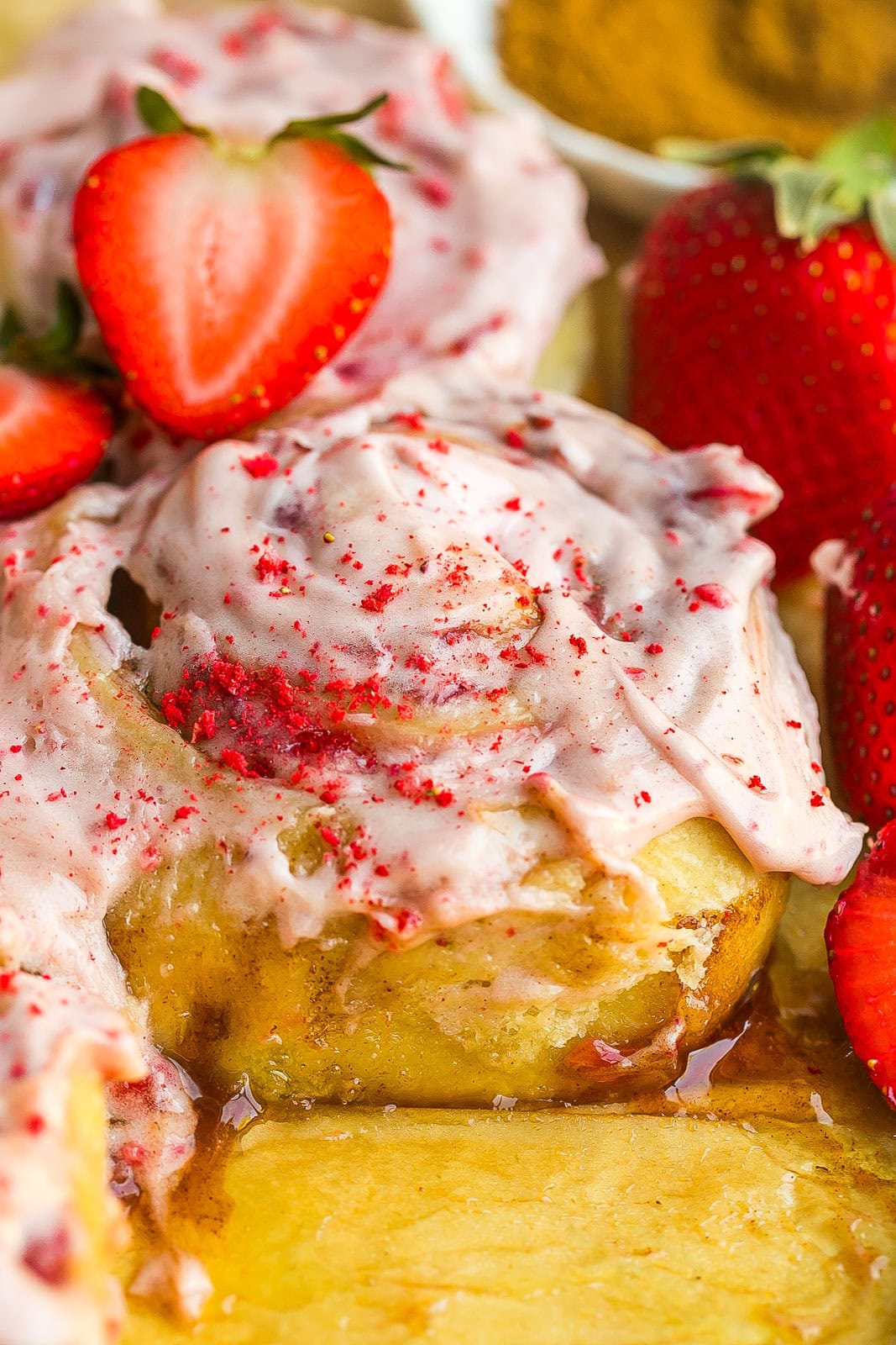Bakery-style Strawberry Cinnamon Rolls topped with strawberry frosting.