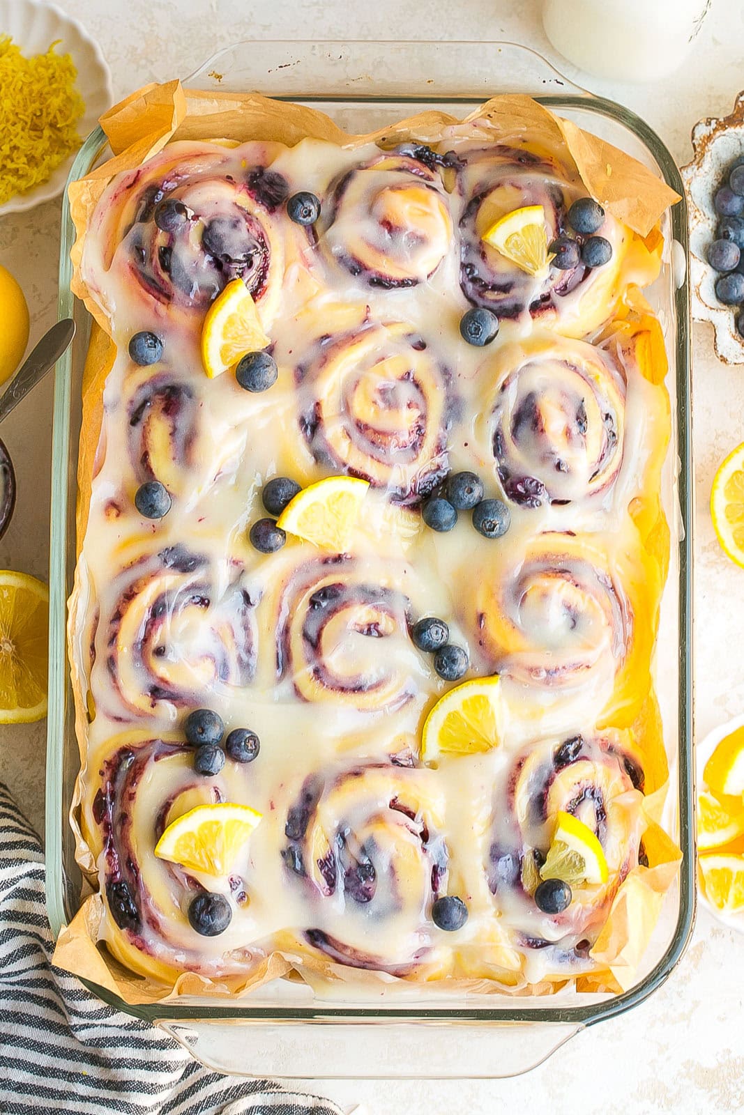 Blueberry lemon sweet rolls topped with lemon cream cheese icing in a baking dish.