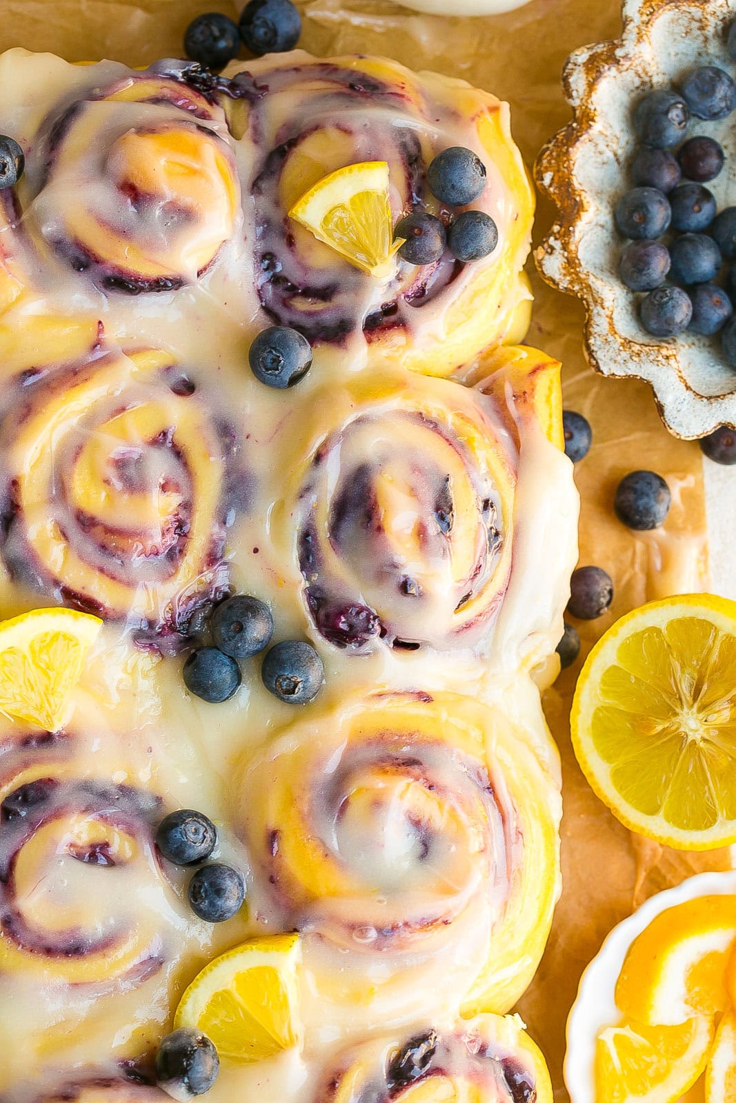 Close-up, birds eye view of a blueberry lemon sweet roll showing swirls of blueberry filling and lemon icing.