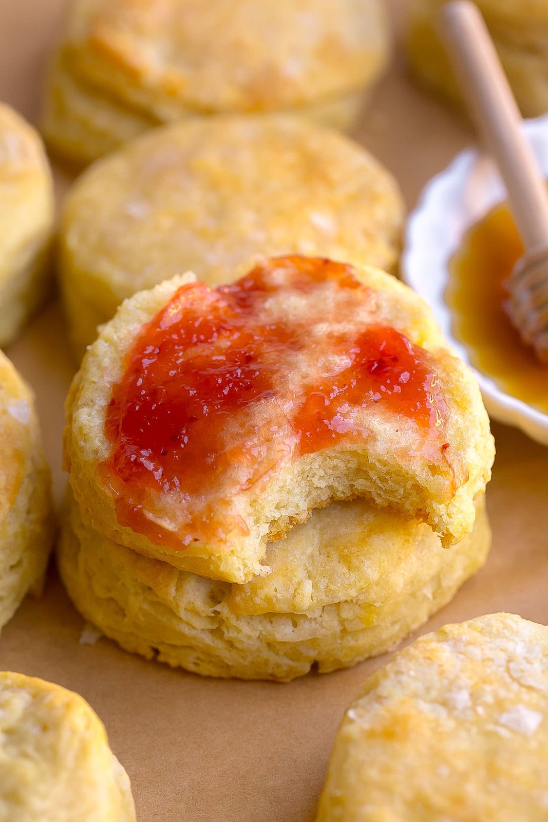 A flaky buttermilk biscuit with jam and a bite mark.