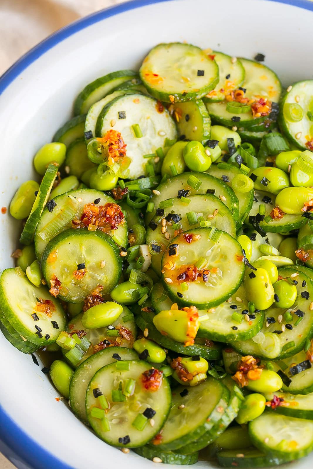 Easy Edamame and Cucumber Salad served in a bowl with sliced cucumbers, edamame, green onions, and sesame seeds.