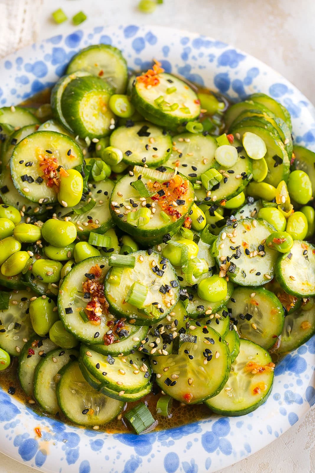Blue splattered bowl with cucumber edamame salad, coated in sesame ginger dressing.