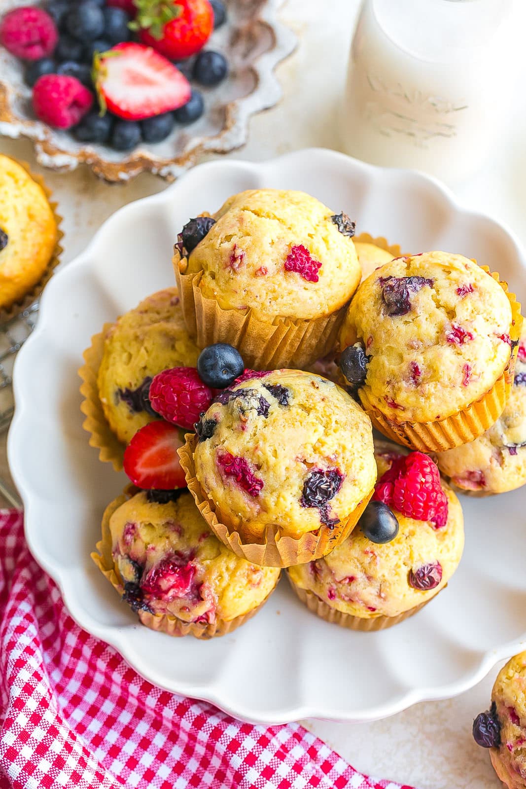 A white bowl with Triple Berry Muffins that are perfectly golden brown on top.