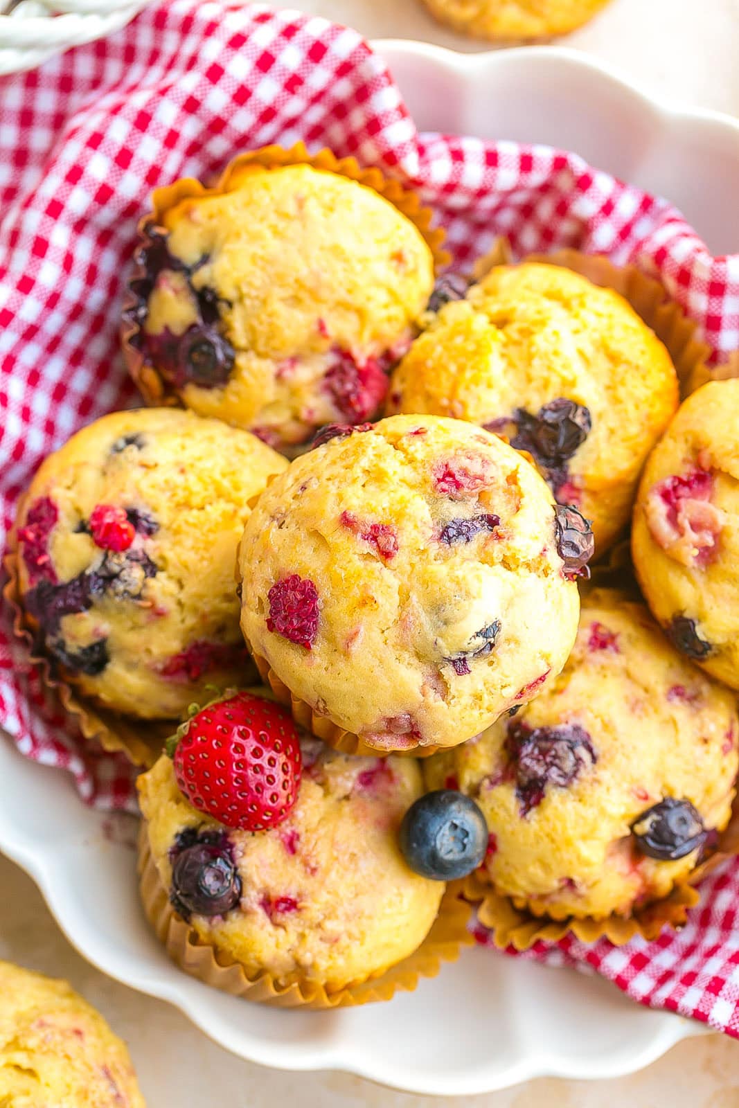 A white bowl with homemade Mixed Berry Muffins made with blueberries, raspberries, and strawberries.