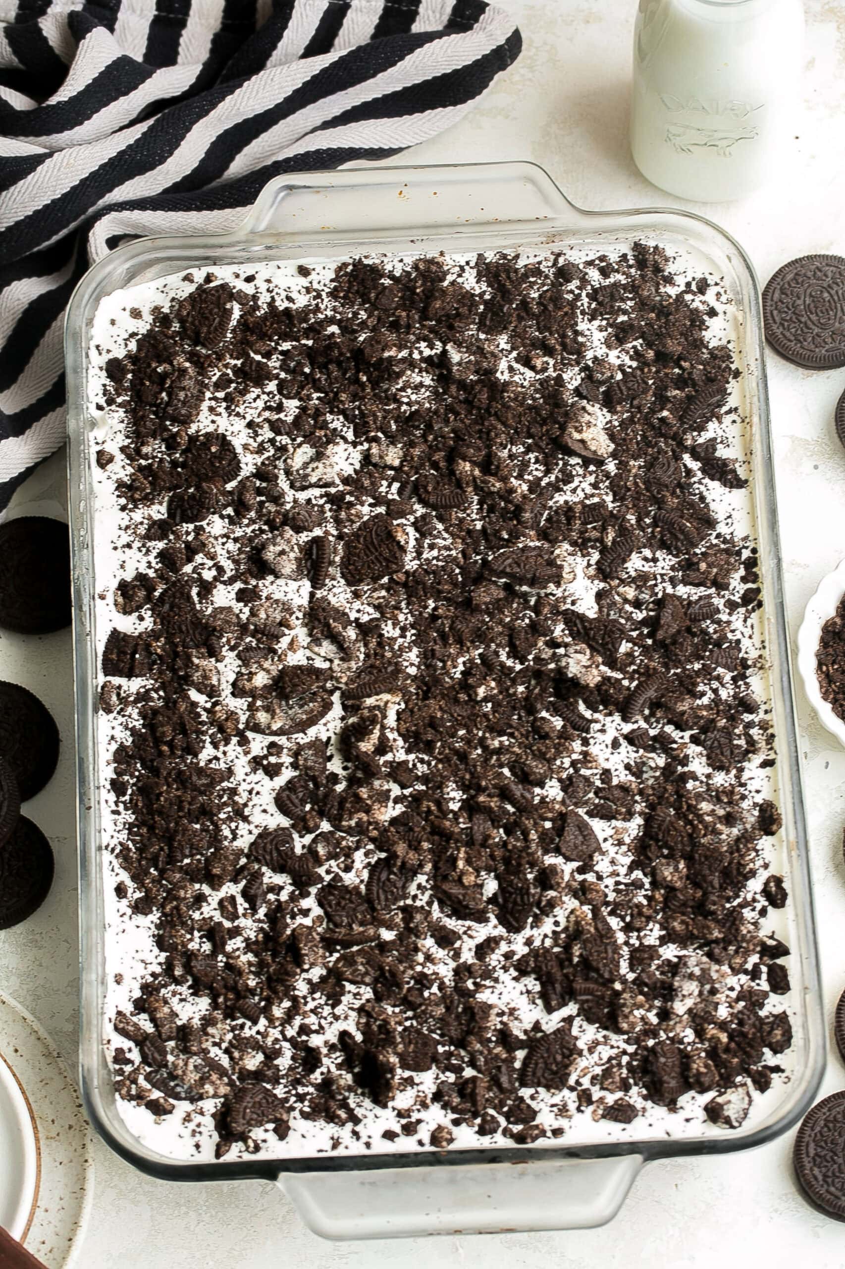 An Oreo Poke Cake with chocolate cake, cookies and cream pudding, whipped topping and crushed Oreo cookies.